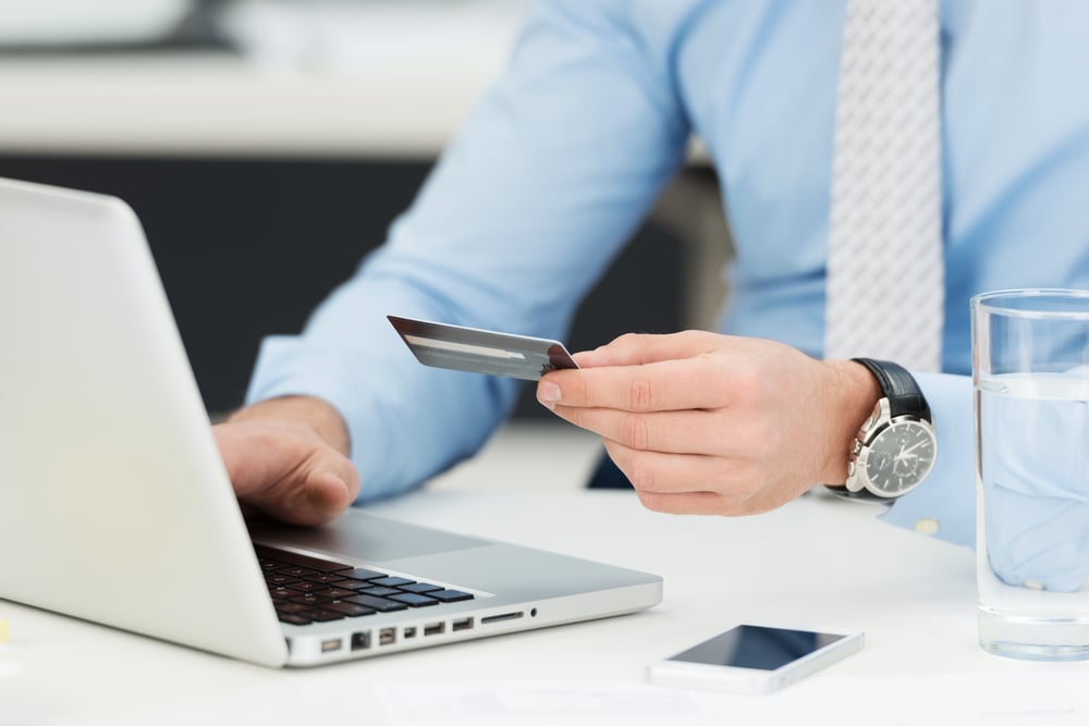 Businessman in need of debt support entering his credit card details on a laptop